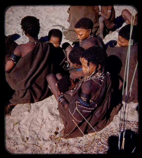 Woman nursing a baby, sitting with a group of people