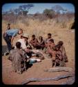 Group of people sitting, receiving mealies from Fritz Metzger and Carey McIntosh