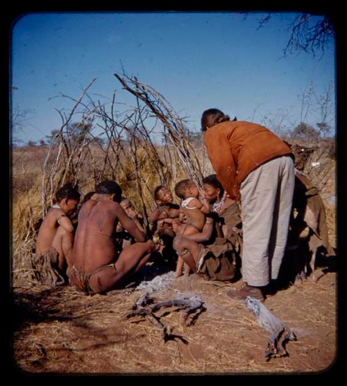 Group of people sitting, with Lorna Marshall bending over them