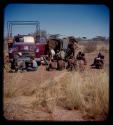 Group of people sitting next to an expedition truck, waiting to have their face casts made