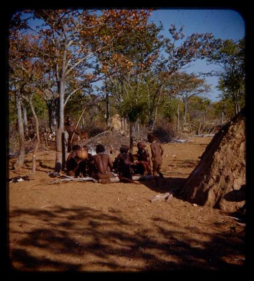 Group of men from Meri Catinga's kraal sitting between a chicken coop and Coutimwe's hut