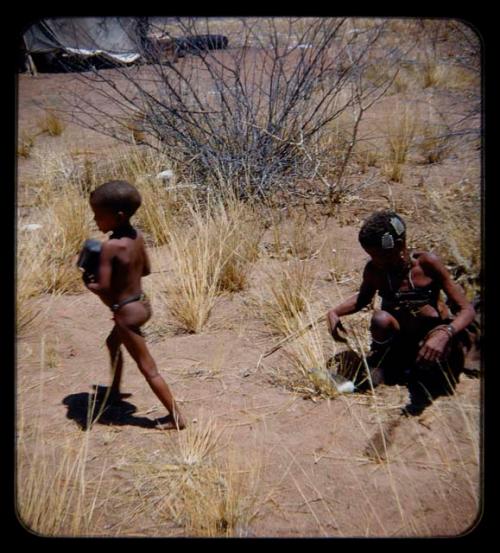 Children, Mothers nursing babies: Woman sitting and a child walking nearby, with a tent in the background