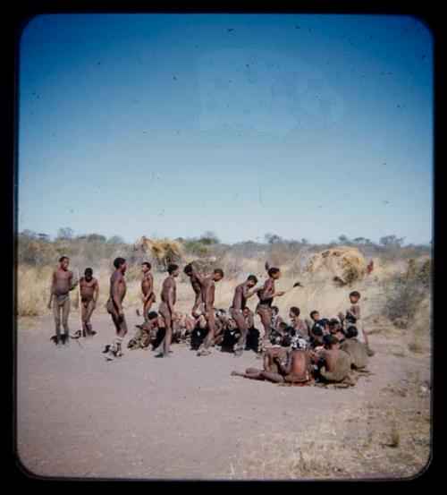 Dance: Group of men performing a curing dance around seated women