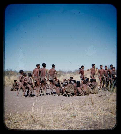 Dance: Group of men performing a curing dance around seated women