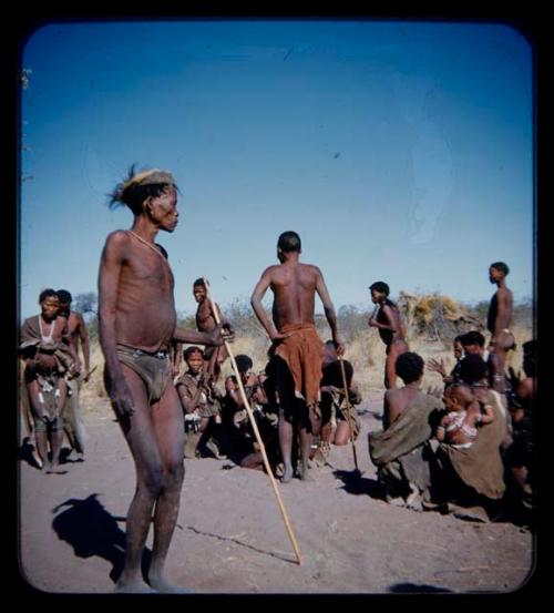 Dance: Group of men performing a curing dance around seated women