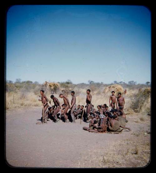 Dance: Group of men performing a curing dance around seated women