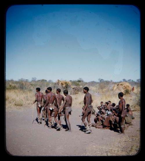 Dance: Group of men performing a curing dance around seated women