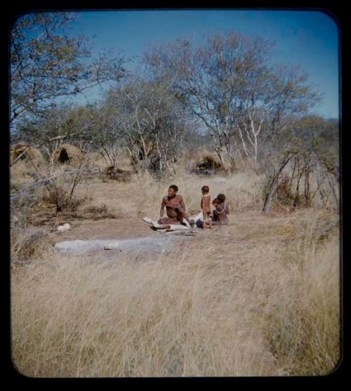 Skerm: Man, a woman, and two children sitting on a white animal hide in front of skerms