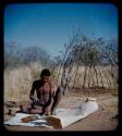 Skerm: Man sitting and working on a white animal hide