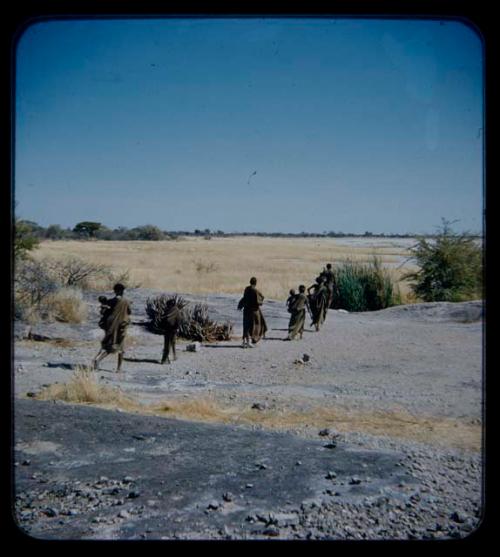 Water: Group of people walking toward pan, seen from behind