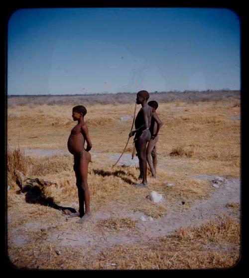 "Young Men": Three young men standing; one man is holding a bow