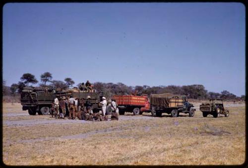 Group visiting expedition members standing by the expedition trucks, in the distance