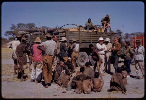 Group visiting expedition members standing by the expedition trucks