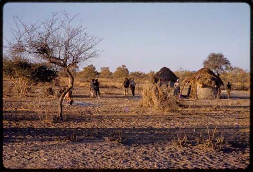 People outside in the area between huts