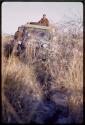 /Gishay and Simon Molamo on top of expedition truck driving through thick brush