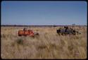 Expedition red Dodge and GMC driving through a grass field