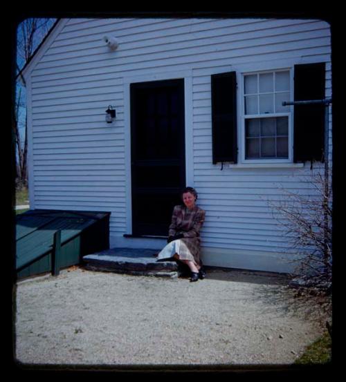 Lorna Marshall sitting on a step in front of the door of a house