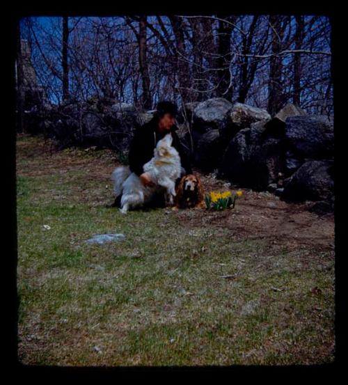 Woman sitting with two dogs in front of a rock wall