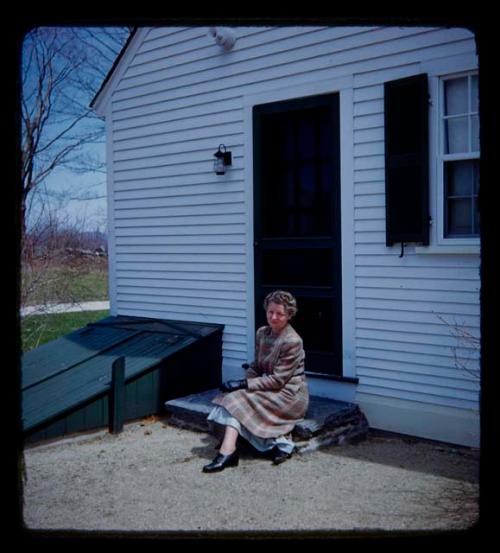 Lorna Marshall sitting on a step in front of the door of a house