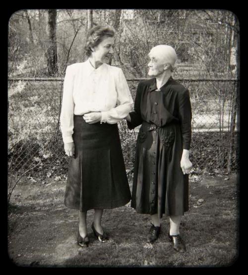 Lorna Marshall standing with another woman in front of a fence