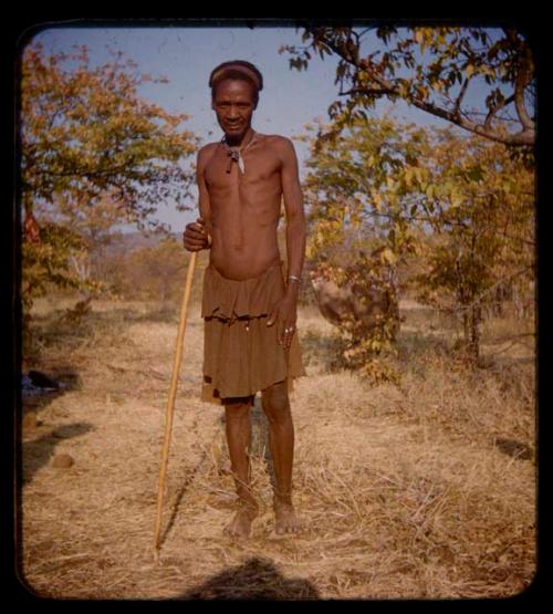 Taindgi standing, holding a stick