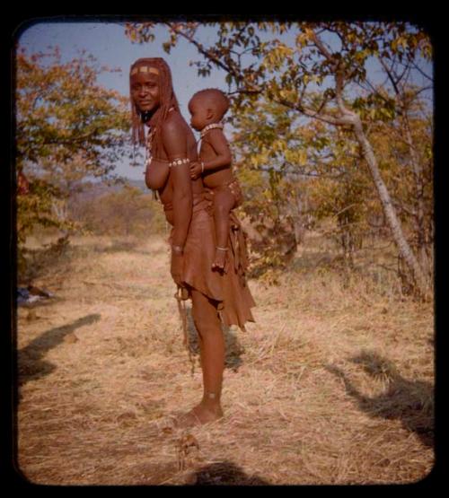 Milandaon standing, carrying a baby on her back, profile