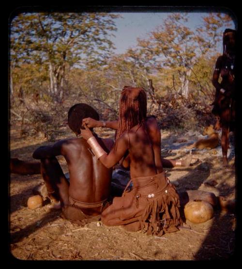 Capepe styling her husband Kanakele's hair, view from behind