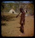 Tschissungo standing, blowing a cattle horn, profile