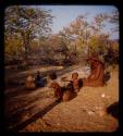 Inunjamo sitting with a baby and a dog near a cooking fire