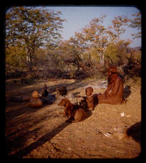 Inunjamo sitting with a baby and a dog near a cooking fire