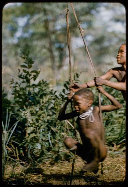 Boy on a swing, being pushed by another boy