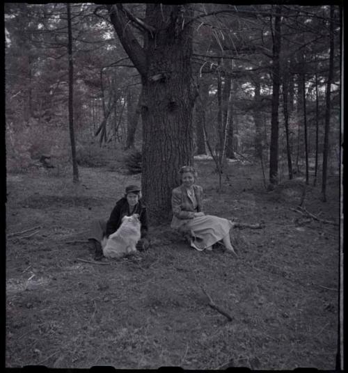 Lorna Marshall and another woman sitting next to a tree with a dog