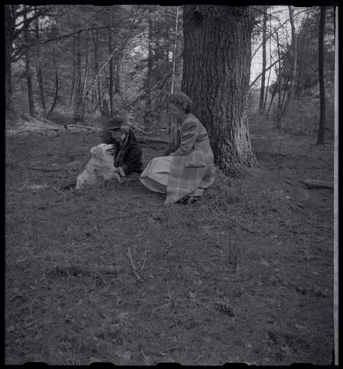 Lorna Marshall and another woman sitting next to a tree with a dog