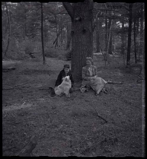 Lorna Marshall and another woman sitting next to a tree with a dog