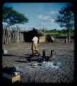 Expedition: Expedition member walking by cooking fire ashes at the expedition camp