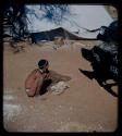 Expedition: Man squatting and facing a truck, with a tent in the background