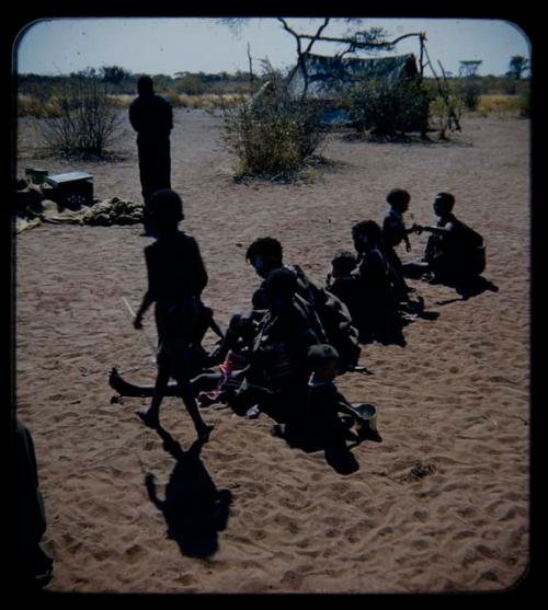 Expedition: Women and children sitting at the expedition camp, seen from behind