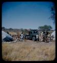 Expedition: Group of people and expedition members, including Laurence Marshall, gathered near a truck and tents