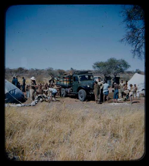 Expedition: Group of people and expedition members, including Laurence Marshall, gathered near a truck and tents