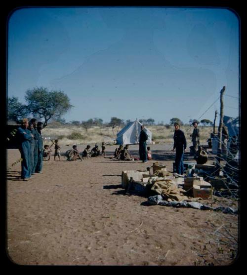 Expedition: Expedition members, including Lorna Marshall, standing at the campsite, with a group of people sitting in the background