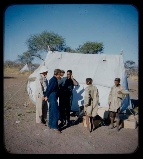 Expedition: Laurence Marshall, Lorna Marshall, and Kernel Ledimo talking to men wearing shirts near a tent