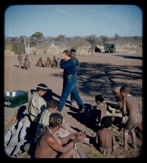 Expedition: Group of people sitting and looking through gifts, with Lorna Marshall and Kernel Ledimo in the background