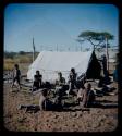 Expedition: Group of people sitting by a tent, with Lorna Marshall and Kernel Ledimo standing in front of a tent in the background