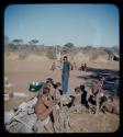 Expedition: Group of people sitting and Kernel Ledimo standing nearby, with another group of people sitting in the background