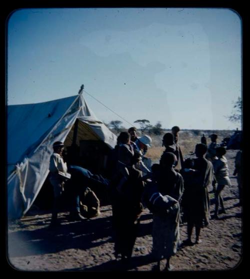 Expedition: Laurence Marshall probably handing out gifts to a group of people in front of a tent