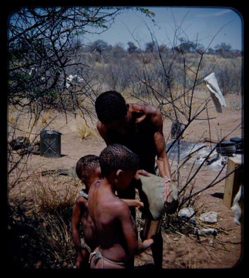 Expedition: Man showing a hat to two boys