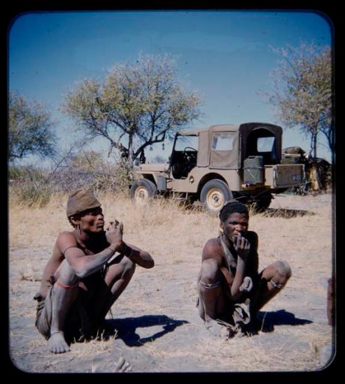 Expedition: Two men squatting on the ground, with Expedition Jeep in the background