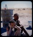Expedition: Woman and a girl sitting by oil or water drums