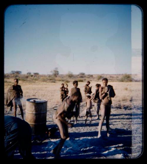 Expedition: Group of men standing near a drum on fire; one man appears to be dancing