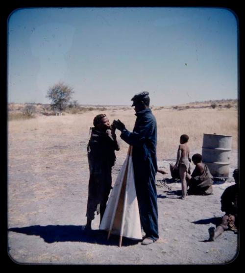 Expedition: Expedition member lighting a pipe for another person